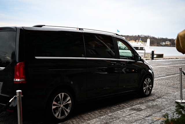En svart Mercedes V-Klass företagslimousine som står parkerad utanför ett hotell, redo att köra en kund till ett möte.